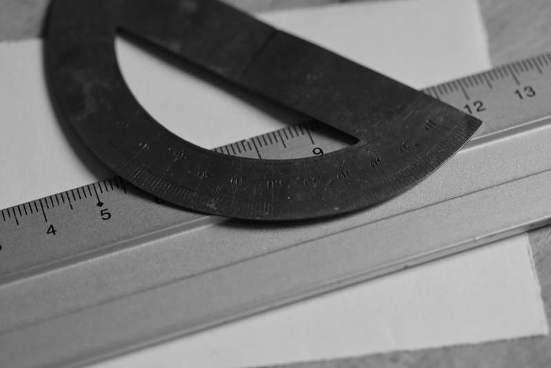 Stylish open shelf displaying vintage and modern protractors alongside design books and artisanal tools
