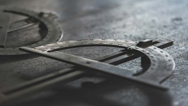 Wooden desk with a brass protractor, measuring tape, and blueprint sketches for home decor projects
